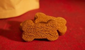 Ginger cookies int he shape of dog bones sit on a red tablecloth