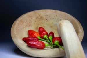 Cayenne peppers in a mortar bowl with pestle 